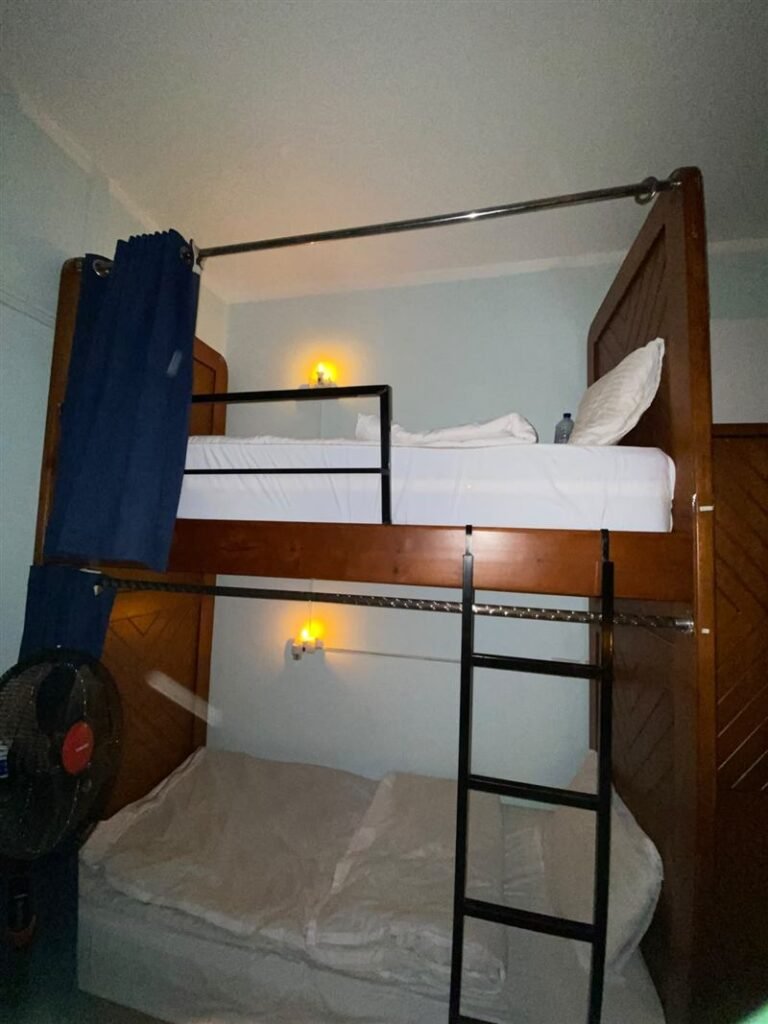 Wooden bunk bed with reading lights and a fan in the dorm