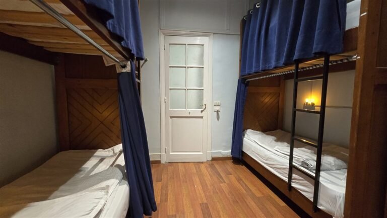 Bunk beds with blue curtains and a white door in the dorm
