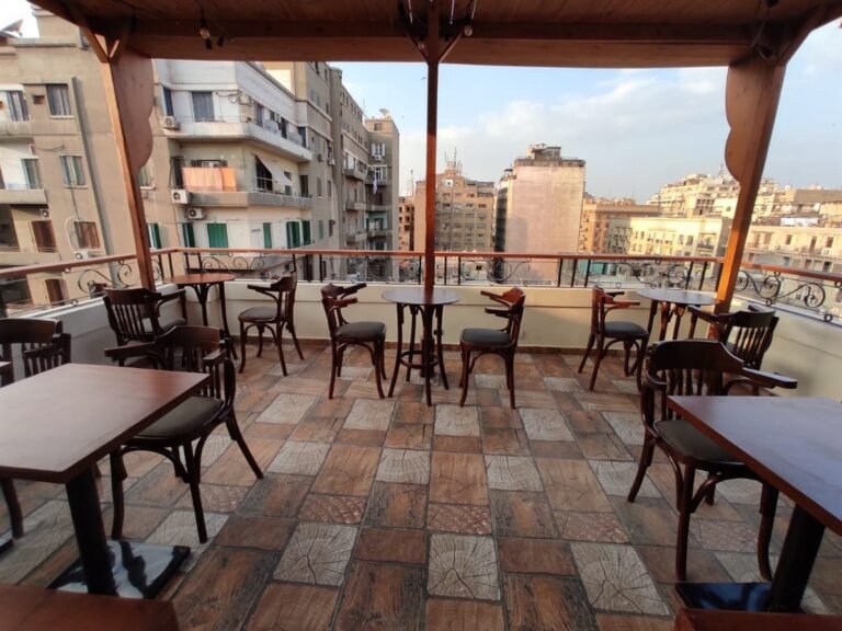 Rooftop terrace with wooden tables and chairs and views over Downtown Cairo