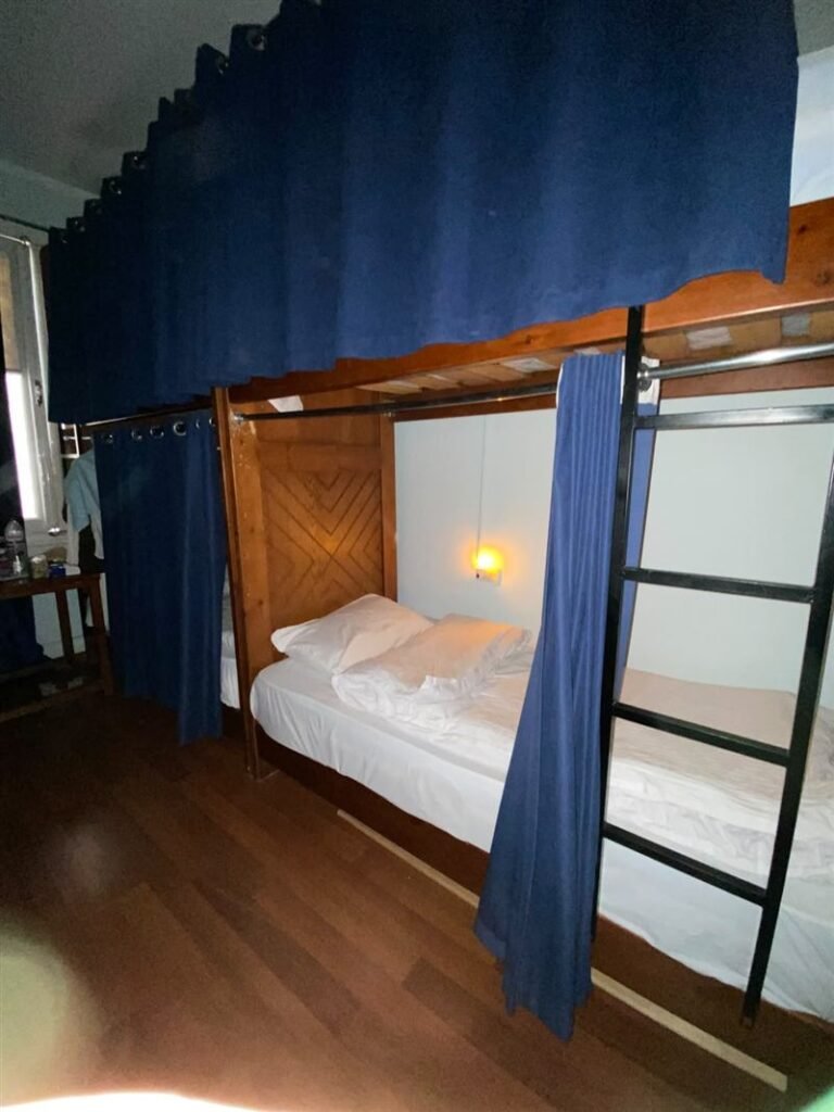 Bunk bed with a blue curtain and a ladder in the dorm