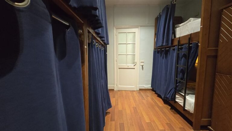 Dorm room with blue bed curtains and a white door