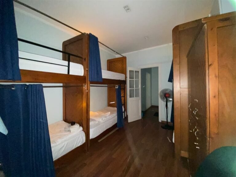 Dorm room with wooden bunk beds, blue curtains and a wardrobe at Cairo House Hostel