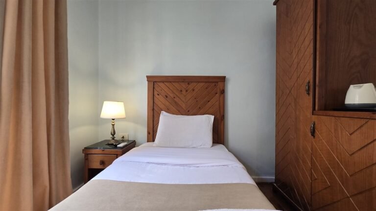 Single room with a wooden bed, a bedside lamp and a carved wooden cabinet