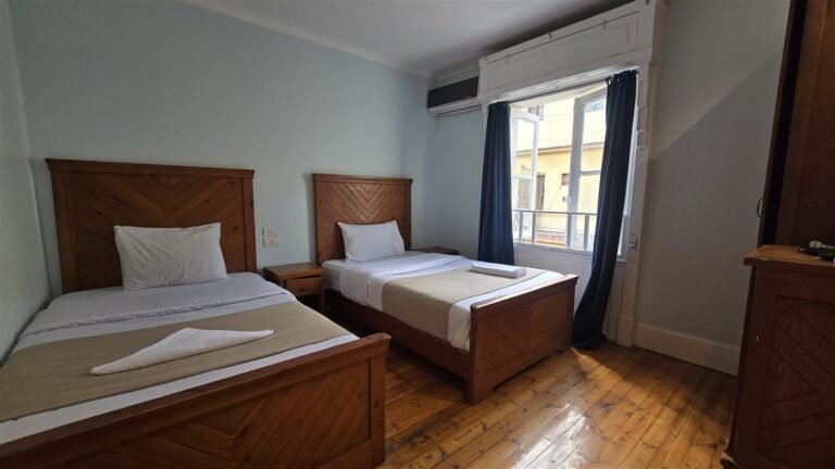 Triple room at Cairo House Hostel with beds, wooden headboards and a window onto the street