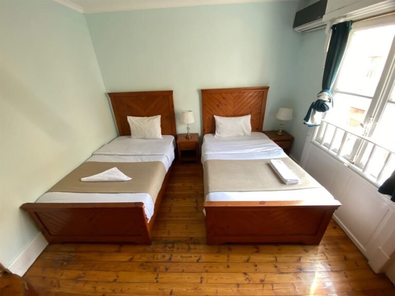 Triple room beds with bedside tables, lamps and a wooden floor